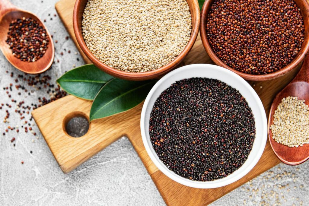 Red, black and white quinoa seeds on a concrete background